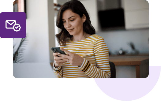 A woman in a yellow-striped shirt types on her mobile phone.