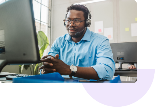 A customer service agent wearing a headset talks to a customer in front of his computer.