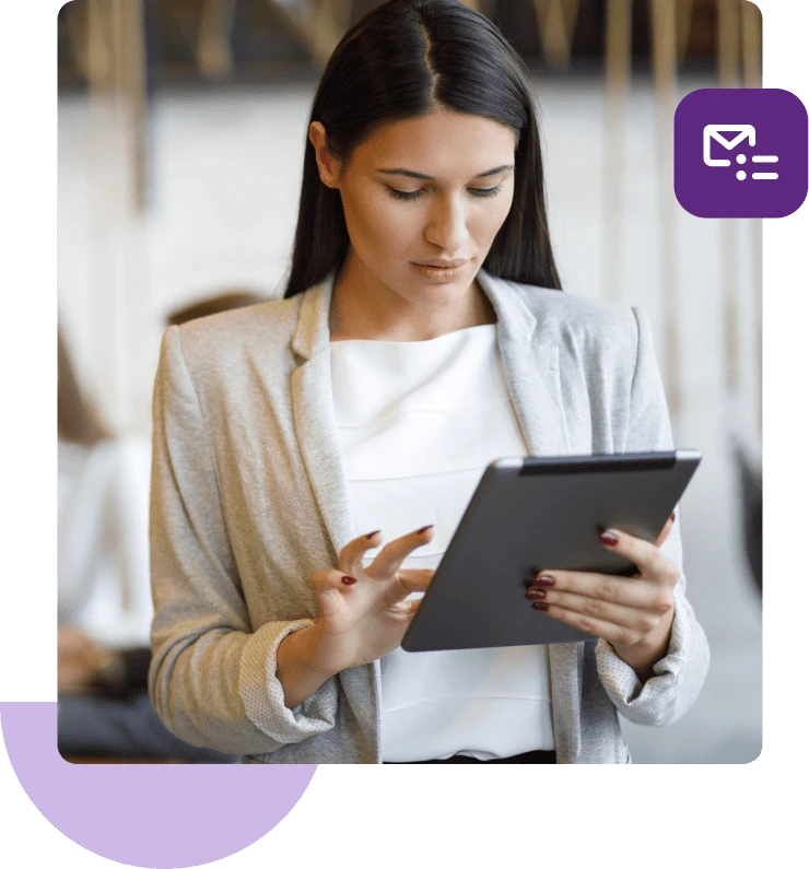 Una mujer con una camisa blanca y una chaqueta beige mira hacia abajo y toca su tableta.