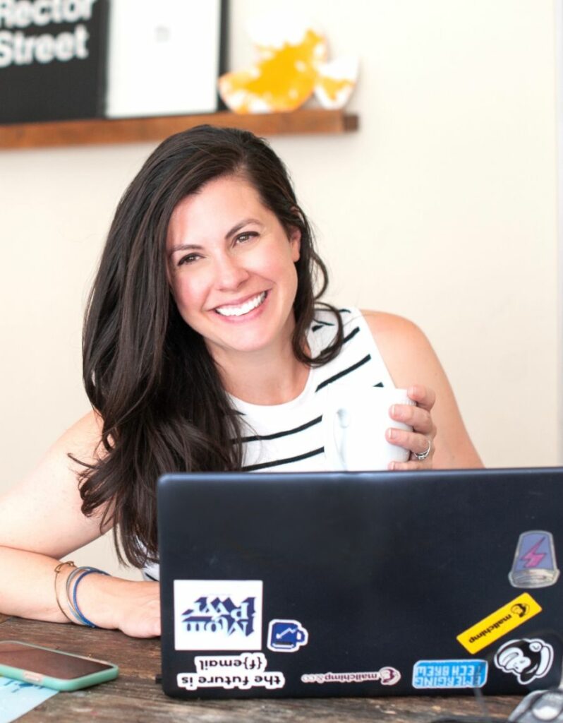 Email marketing expert Emily Ryan sitting in front of a laptop smiling with a coffee mug in her hand tells ZeroBounce how she makes money with email list