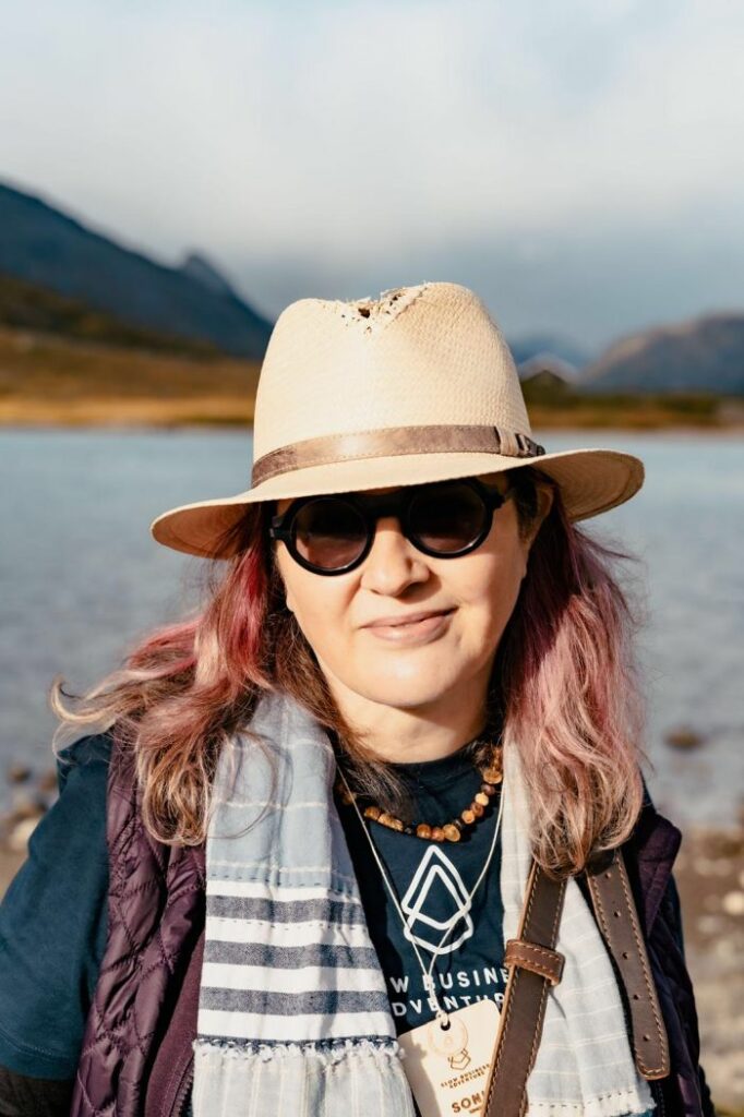 Content marketing expert and Creative Fierce owner Sonia Simone wearing a beige hat and dark sunglasses with mountains and a lake in the background shares her strategy for monetizing email newsletter