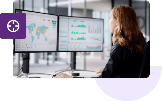 Una toma de una mujer de espaldas mirando dos monitores que muestran mapas de geolocalización y varios gráficos.