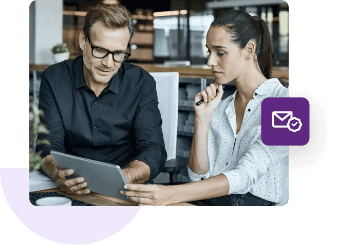 Man and woman sitting at a desk looking at a tablet