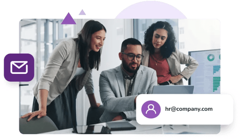 A man in a grey sport coat sits at his desk with two female coworkers flanking either side as he shows the mailbox for 'hr@company.com.'