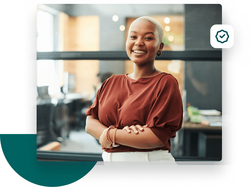 Woman with her arms crossed smiling at the camera from her office