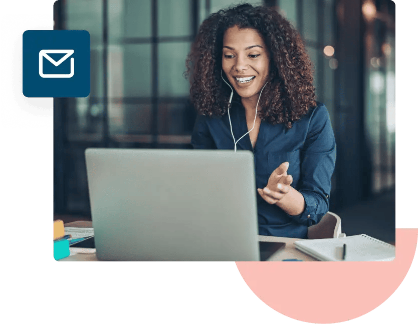 A woman in a blue shirt talks to someone on her laptop while wearing wired white headphones.