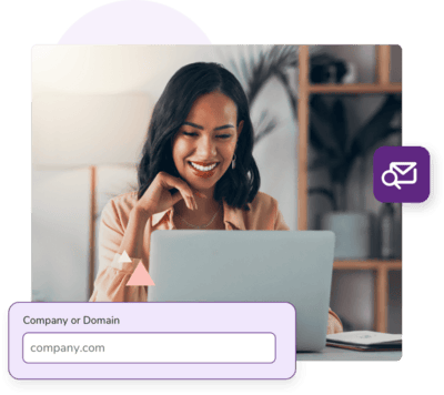 Sitting woman smiles as she looks down at her laptop with a field asking for company or domain