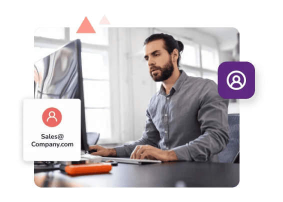 A man in a grey shirt works at his desk with a pop-up showing the role-based email 'sales@company.com.'