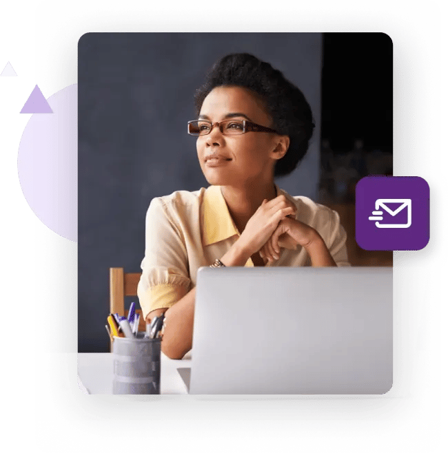 Mujer en su escritorio sosteniendo su smartphone con una laptop de fondo