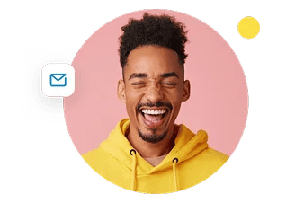 A man in a yellow hooded sweatshirt smiles wide with his eyes closed.