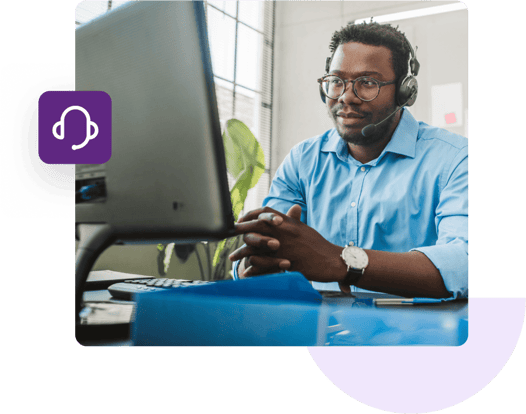 A customer support agent wears a hands-free headset and talks to a customer in front of his computer.