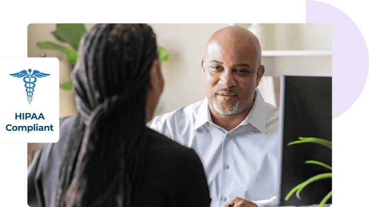 Un hombre y una mujer se sientan uno frente al otro en un escritorio para hablar sobre la seguridad del correo electrónico, acompañados de un logotipo de cumplimiento con la HIPAA.