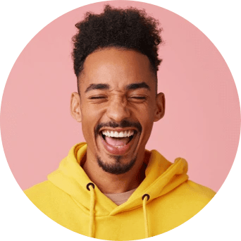 A man in a yellow hooded sweatshirt smiles wide with his mouth open and eyes closed