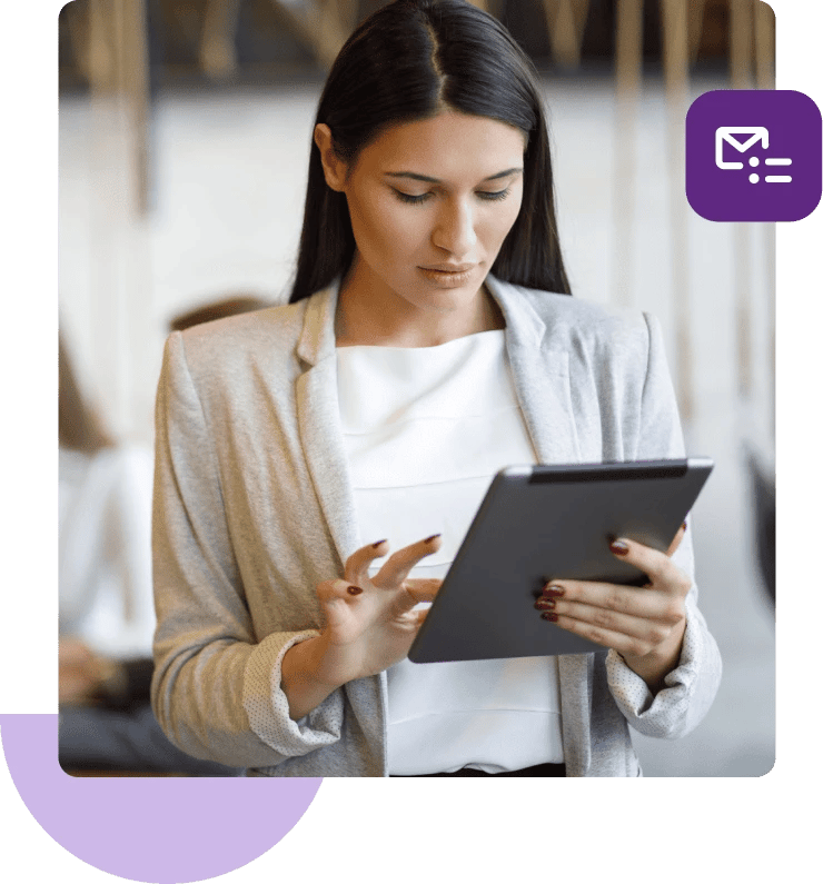 Una mujer con una camisa blanca y una chaqueta beige mira hacia abajo y toca su tableta.