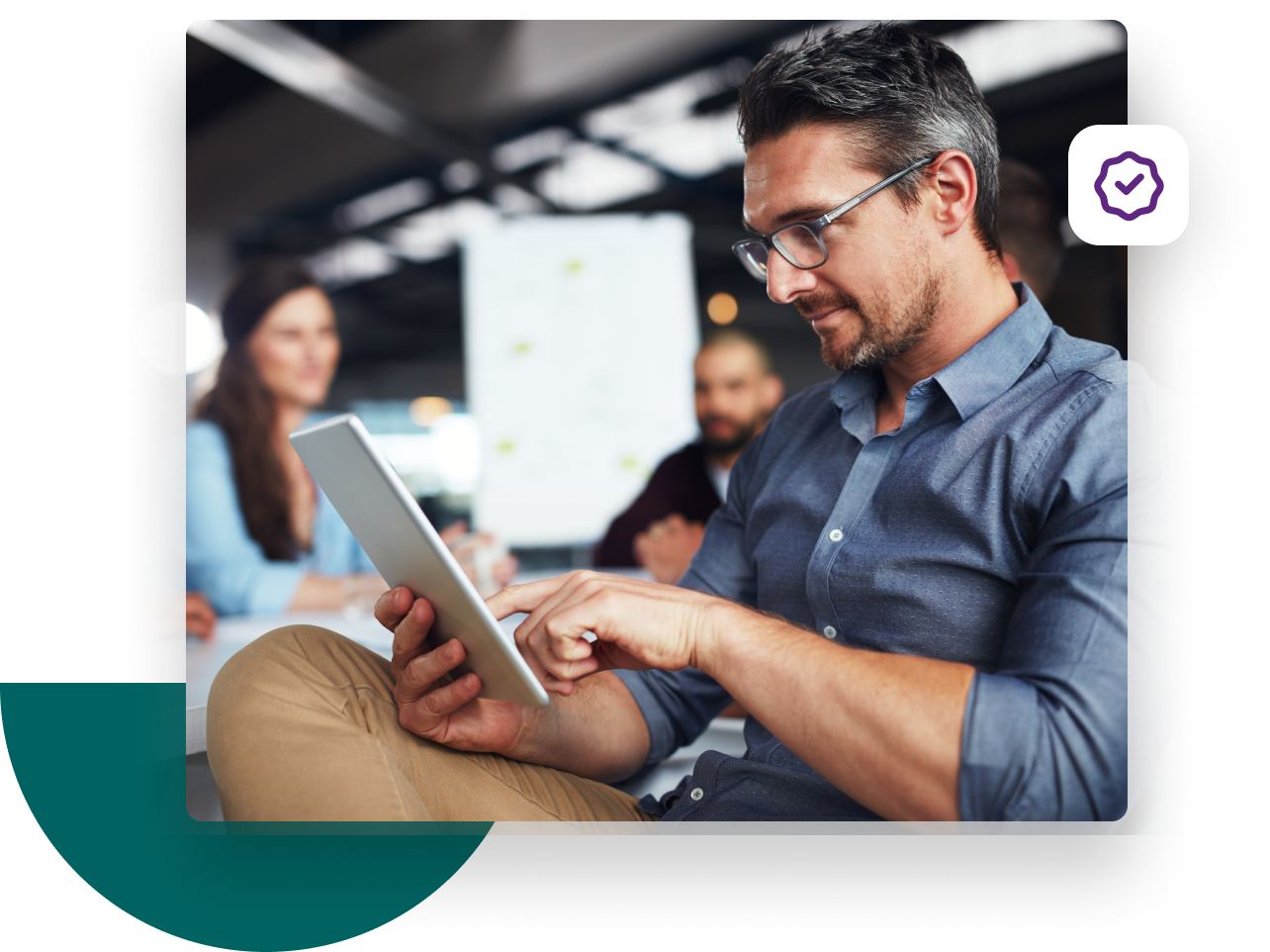 Businessman touching his tablet accompanied by two coworkers out of focus in the background