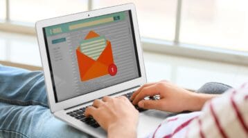 person's hands resting on laptop illustrating the latest ZeroBounce survey that shows most consumers check email daily