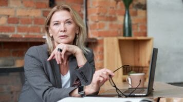 Decision-maker with blonde hair and eyeglasses removed considers reading email.