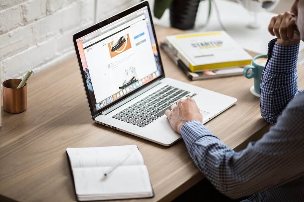 Man sitting at his desk looking at his laptop reading emails. 