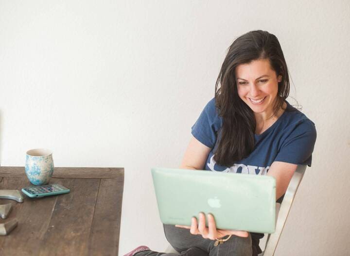 woman looking at her laptop smiling at the personalized subject line of an email.
