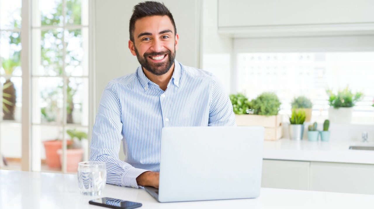 young caucasian man smiling in front of computer while enjoying the benefits of an email finding service