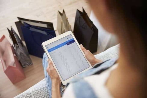 Woman With Shopping Bags Checks Bank Statement On Digital Tablet