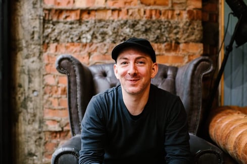 Email marketing expert Simon Harper smiles and sits in a chair at a coffee shop.