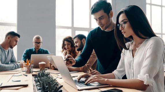 Work colleagues gather around to discuss re-engagement email strategies.