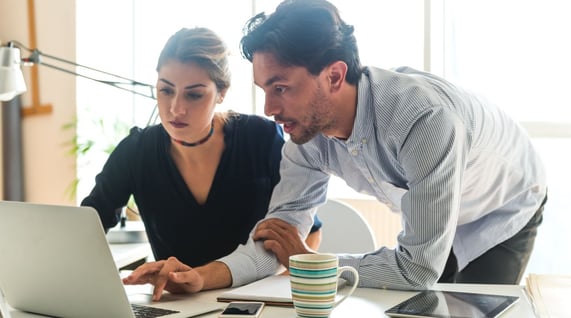 man and woman colleagues checking marketing email on laptop screen for email spam trigger words