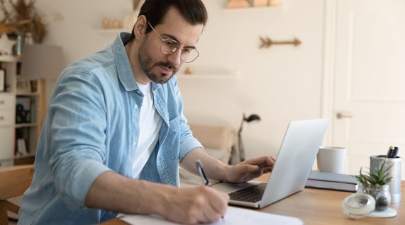 man wearing blue shirt taking notes about the latest email trends for 2024