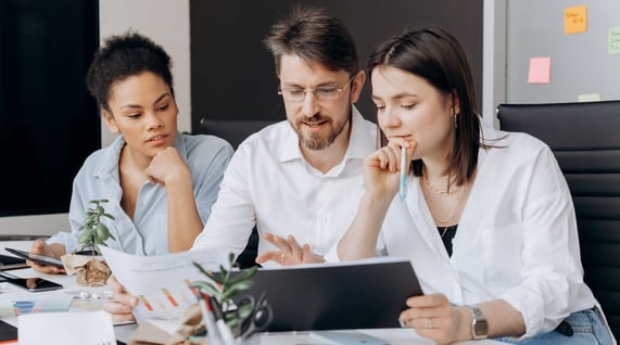 two women and one man colleagues looking at tablet to learn about words that trigger email spam filters