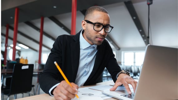 Bespectacled African-American man checks if an email is valid before sending a marketing email