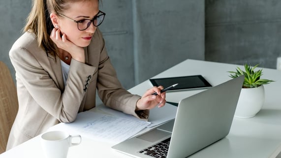 Bespectacled woman sits in front of laptop as she modified email marketing templates.