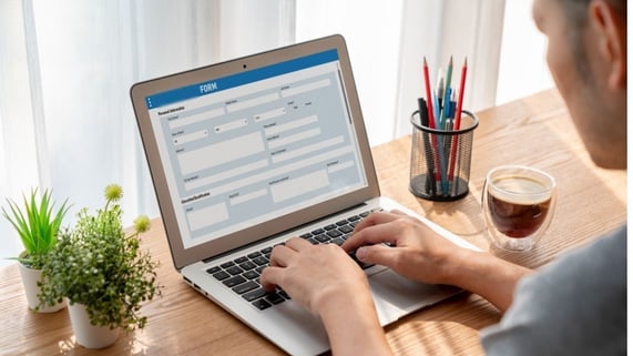 Screenshot of man at laptop using a Google Form with attached email validation API. Coffee cup is nearby.