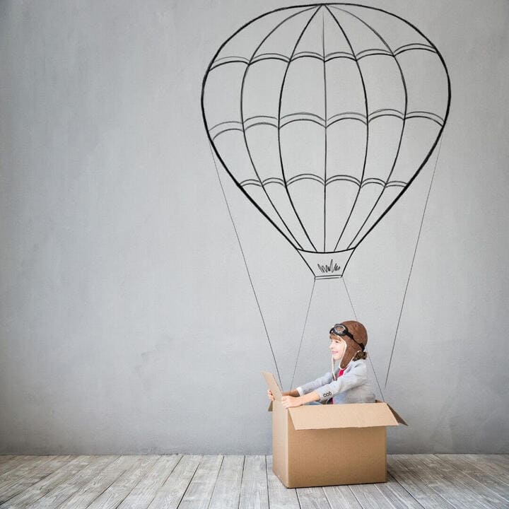 Boy in a box pretending to be in a hot air balloon.