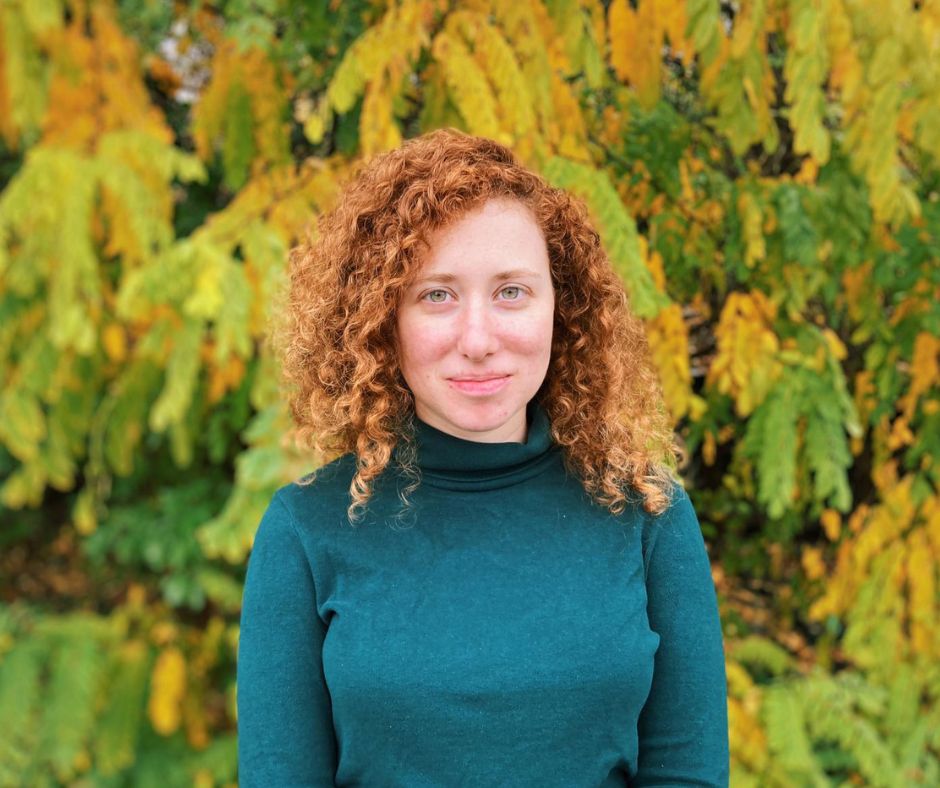 yuval ackerman wearing teal blouse on green background with trees